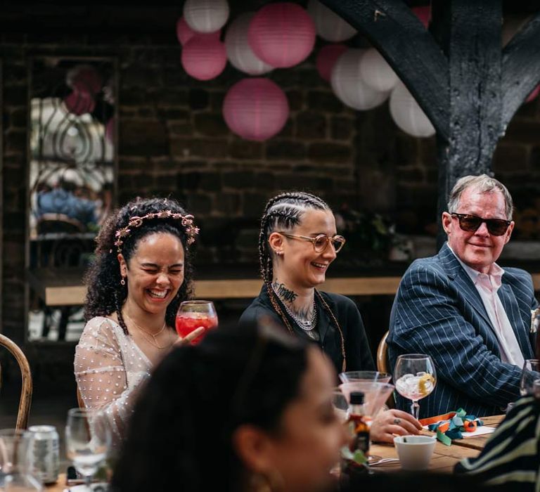 Brides drinking cocktails and laughing at wedding speeches during at-home Viking themed wedding