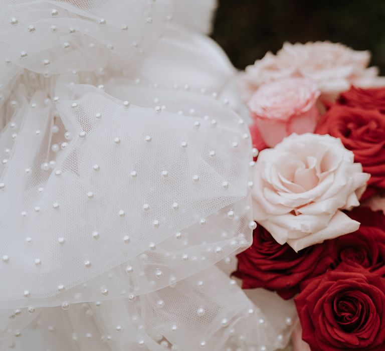 Bride in a statement puff sleeve wedding gown holding deep red and baby pink rose bouquet 