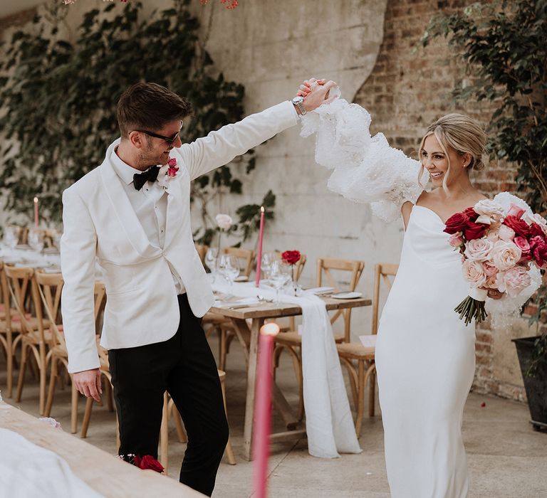 Bride in satin Chosen by Kyha wedding dress with detachable sleeves with groom in white tuxedo at their country house wedding 