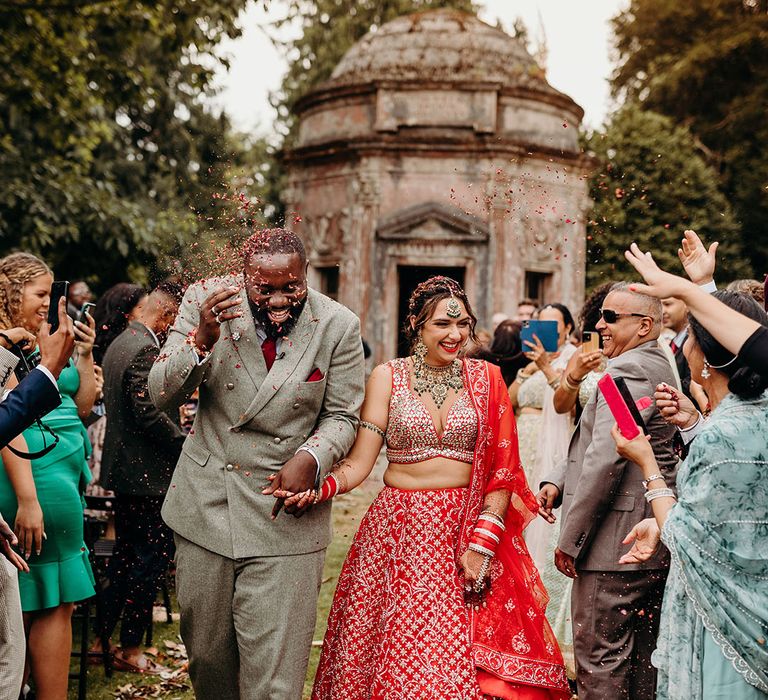 Bright and colourful wedding confetti moment for the bride and groom as they walk down the aisle as a married couple 