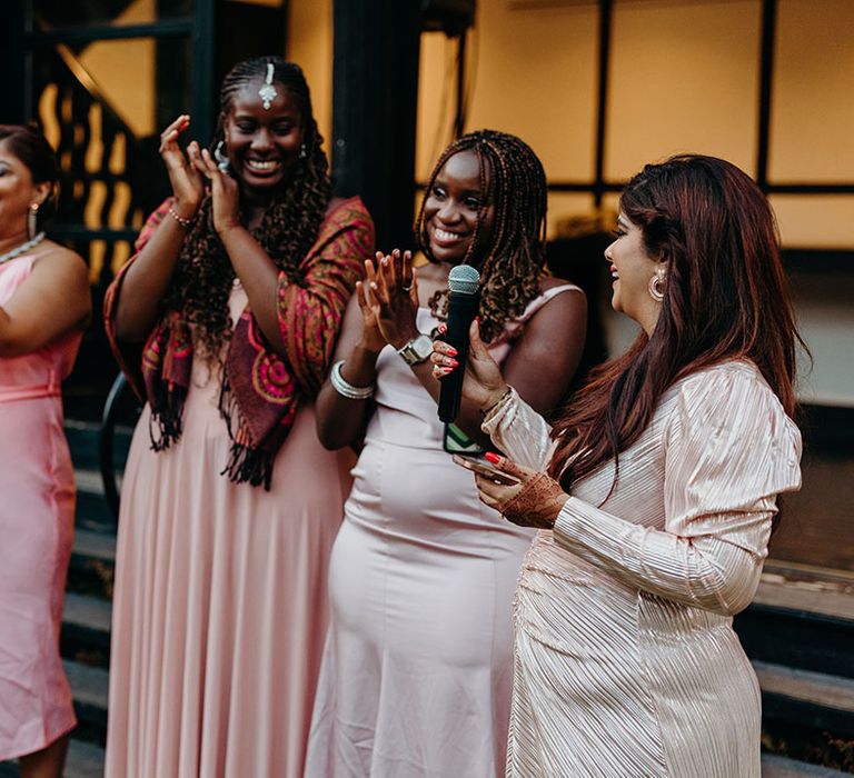 Pink outfits worn by wedding guests as they perform a joint wedding speech 