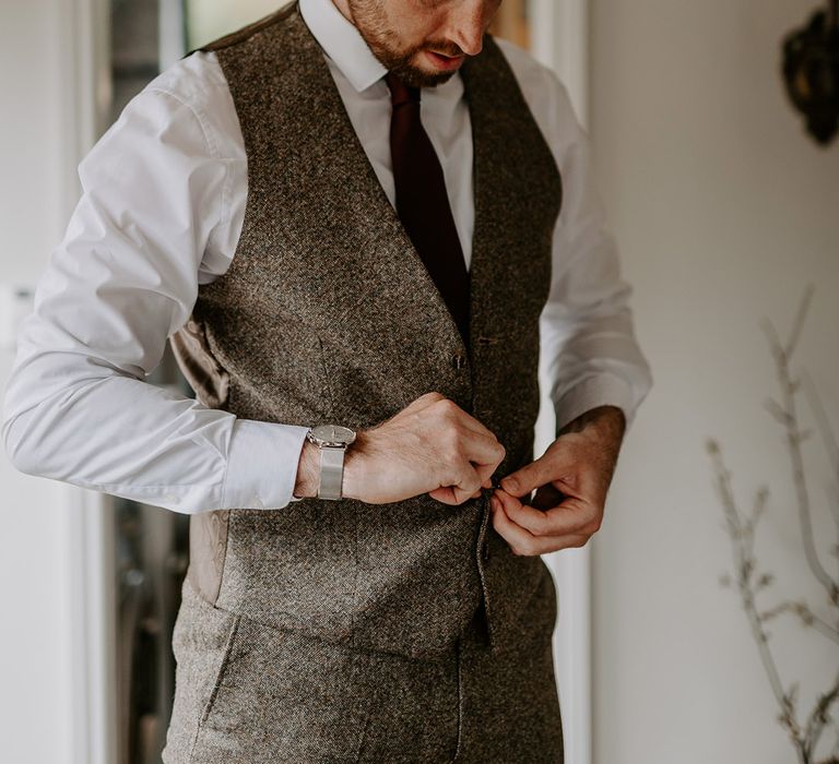 The groom in a grey wedding suit gets ready for the wedding day 