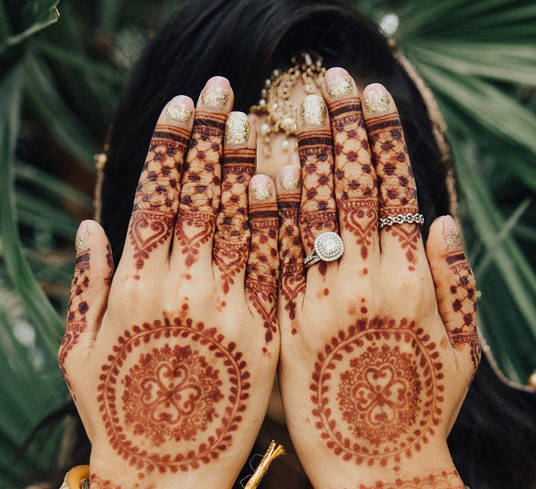 Bride wearing sparkly gold glitter ombre engagement nails with henna pattern