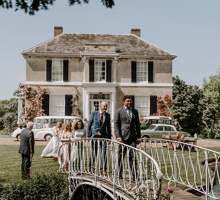 Preston Court country house wedding venue with guests walking over the bridge 