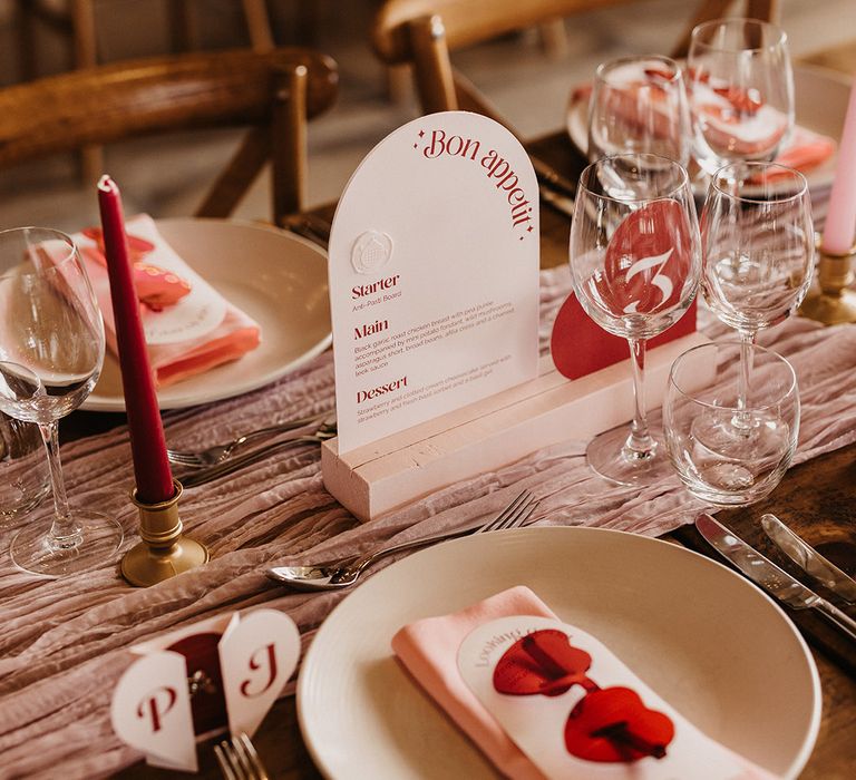 Pink and red wedding theme with heart shaped sunglasses favours with arched wedding menu 