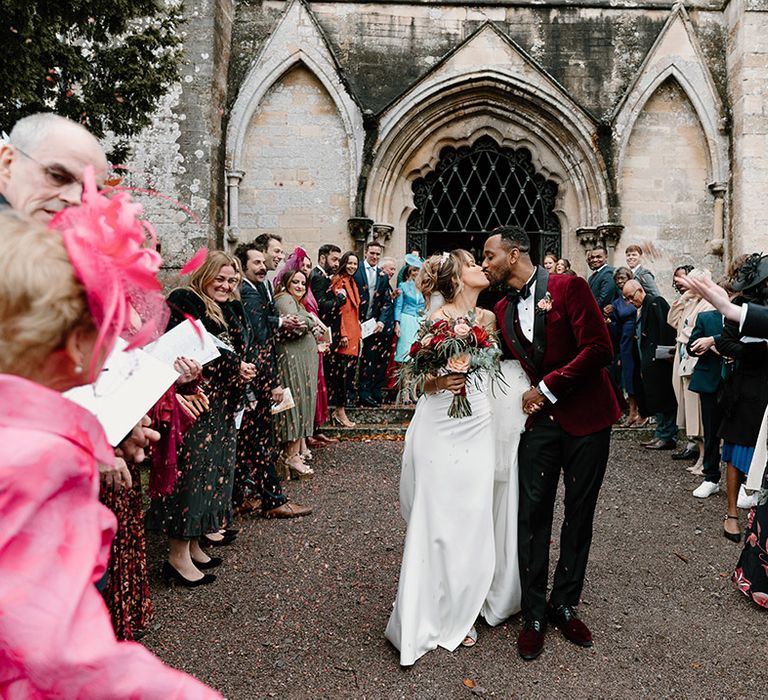 Dried petal confetti is thrown by the guests over the bride and groom at their church wedding 