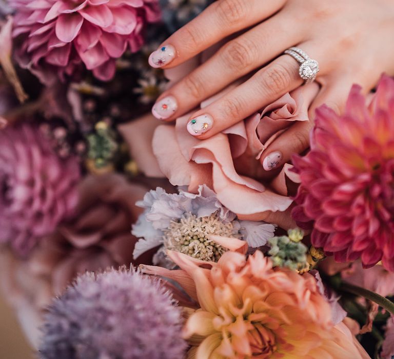 Bride wearing neutral wedding nail with pink french tip design and stars with colourful gems 