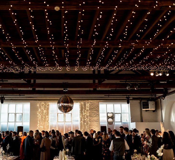 Guests enjoy dinner under fairy light canopy at large wedding