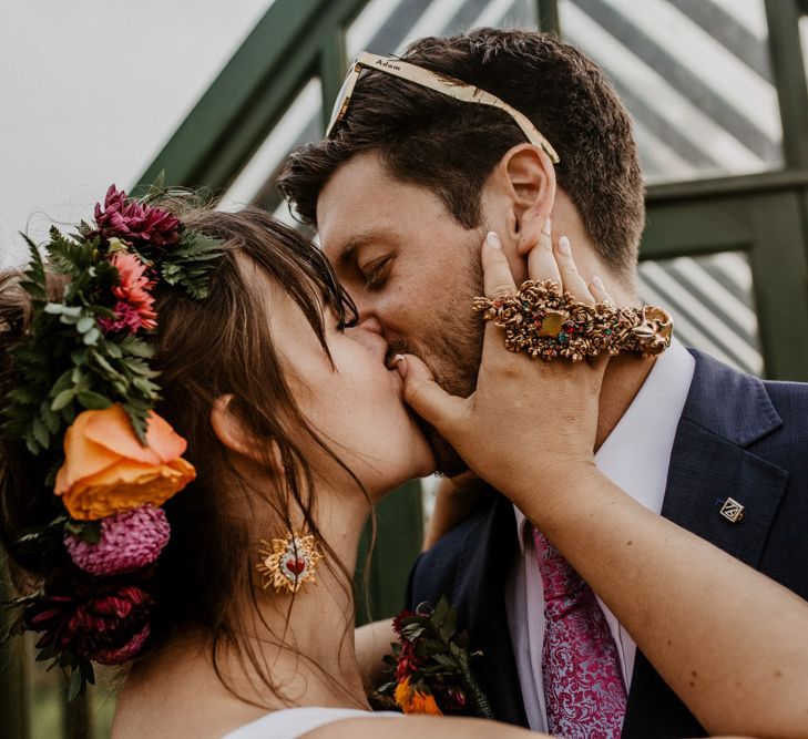 Bride and groom kissing with bride wearing a finger accessory 