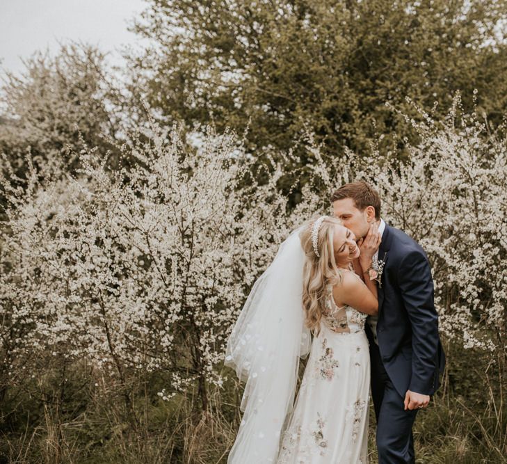 Bride and groom kissing by the Spring blossom