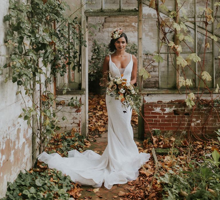 Bride in wedding dress with straps and sequins holding an autumn wedding bouquet 