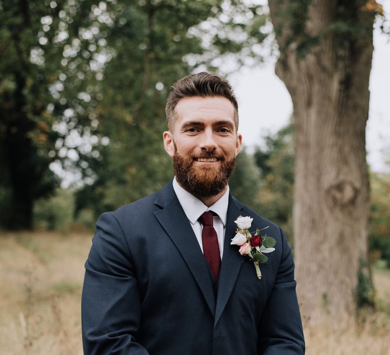 Groom in navy suit with burgundy wedding tie 