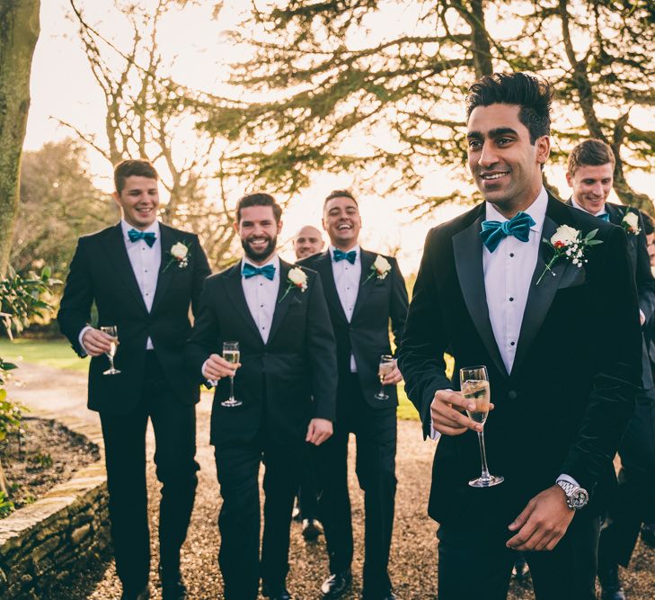 Groom and groomsmen in suits and bow ties for winter wedding 