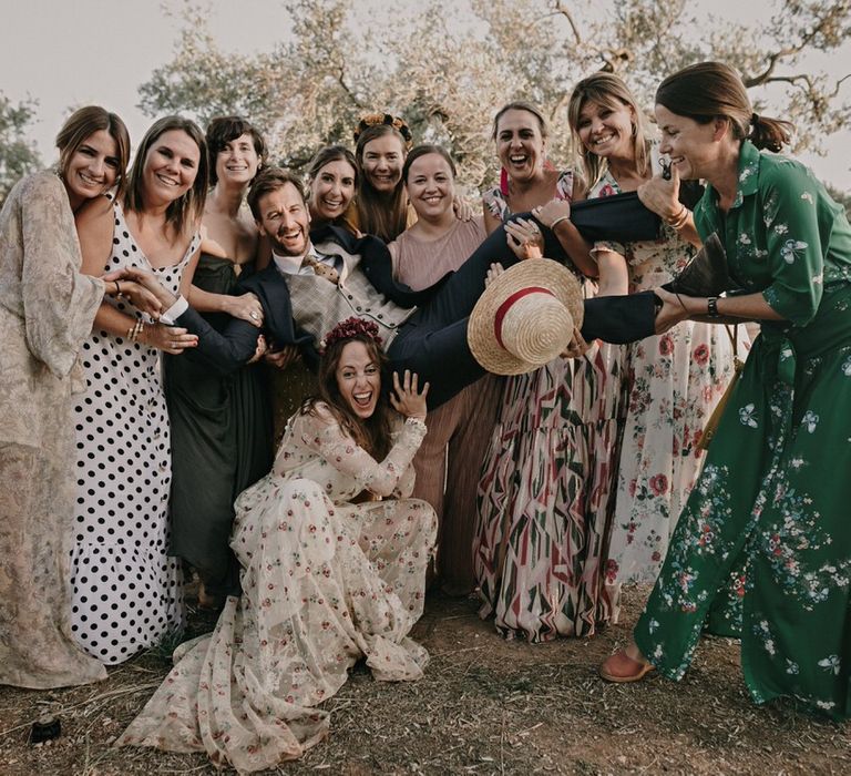 Groom is lifted up by guests and the bride