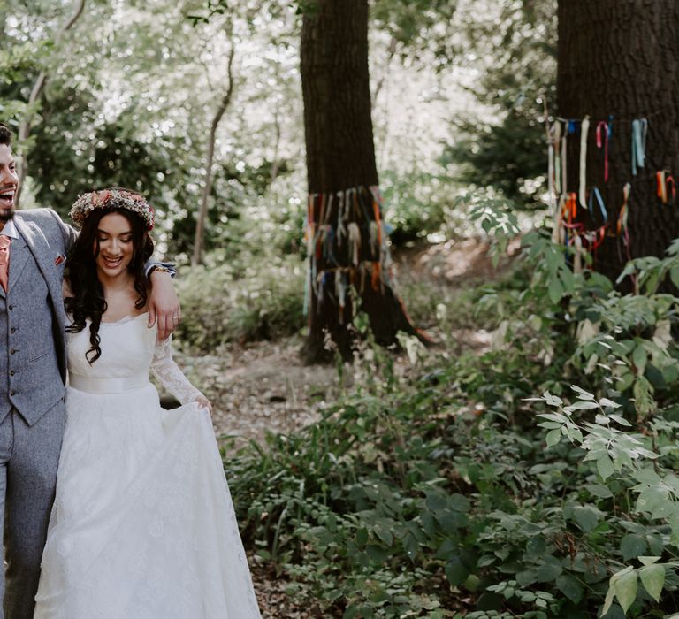 Bride and groom walk through woodland. Bride wears ASOS Bridal dress.