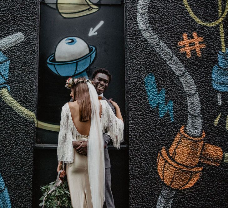 Couple embrace against a graffiti wall