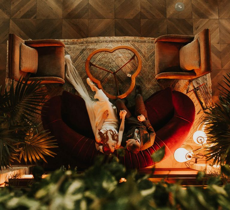 Birds eye view of bride and groom sat on curved velvet sofa for London elopement wedding