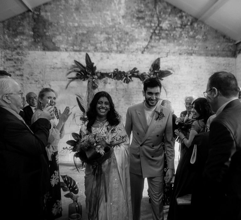 Black and white portrait of the bride and groom walking down the aisle 