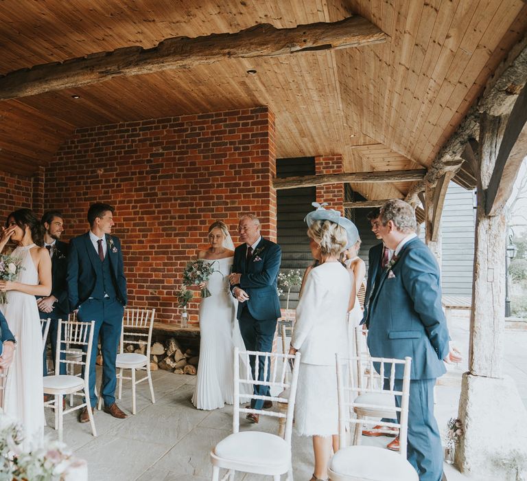 Bride walks down the aisle with her father surrounded by wedding party