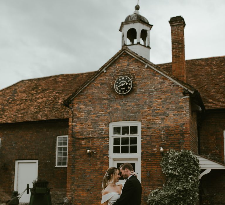 Bride & groom stand within the grounds of the barn 