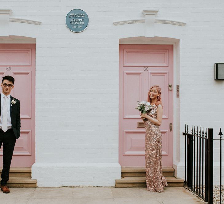 Bride with pink hair in a pink sequin wedding dress standing in front of a pink door in Chelsea