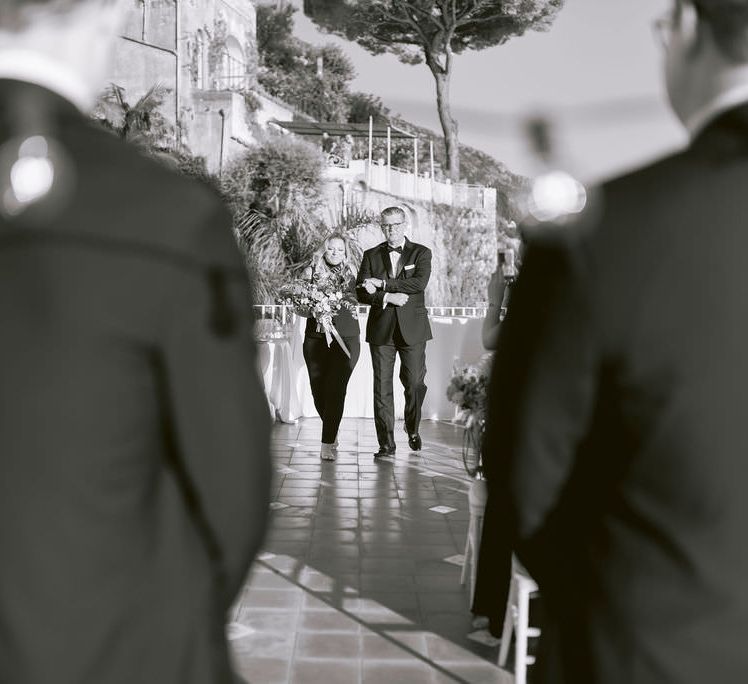 Bride walking down the aisle at Hotel Marincanto wearing a black jumpsuit