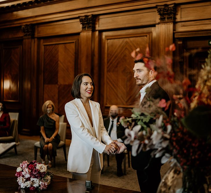 Bride & groom hold hands as they stand at the altar during wedding ceremony