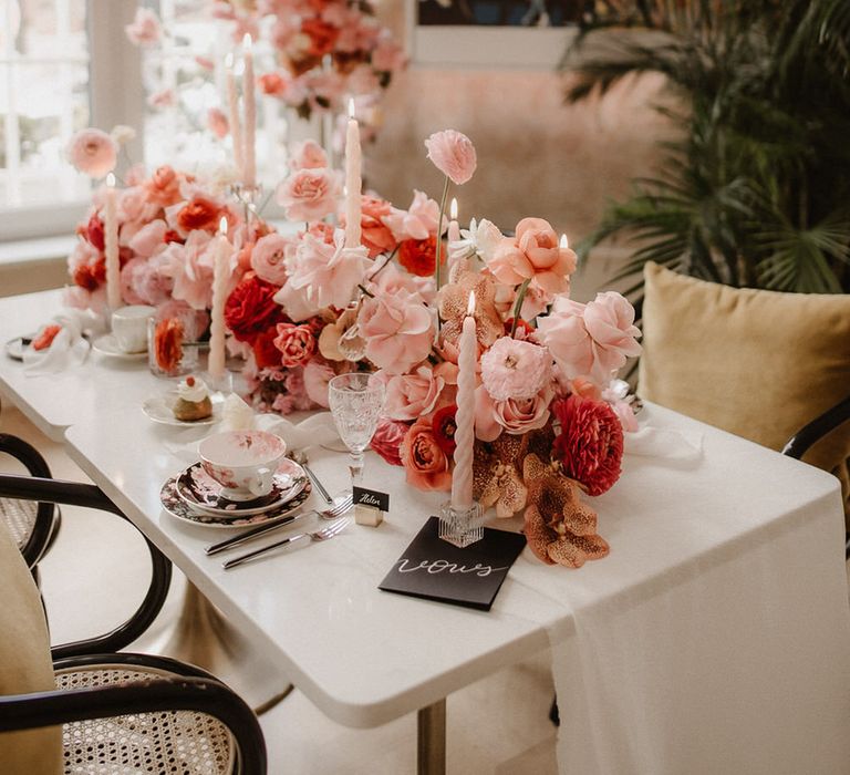 Luxe wedding tablescape with peach wedding flowers including pink, peach and burgundy ranunculi, garden roses and orchids