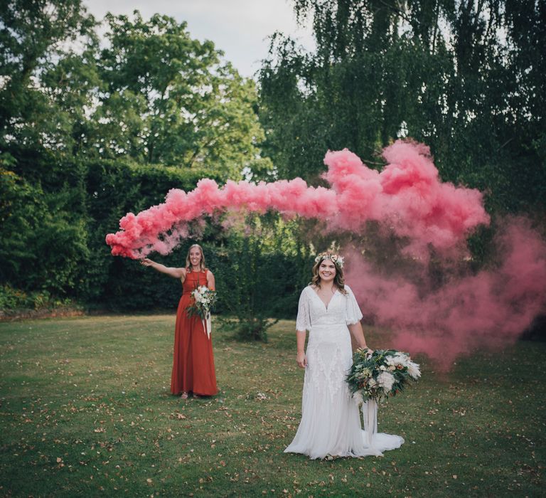 Bride stands beneath pink smoke bomb