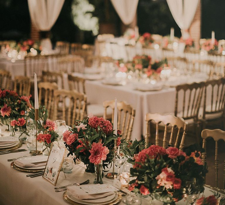 Lanterns hang above wedding reception tables whilst draped fabric can be seen in the background