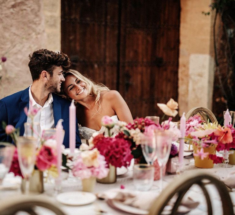 Bride and groom sat at romantic wedding banquet table with pink flowers