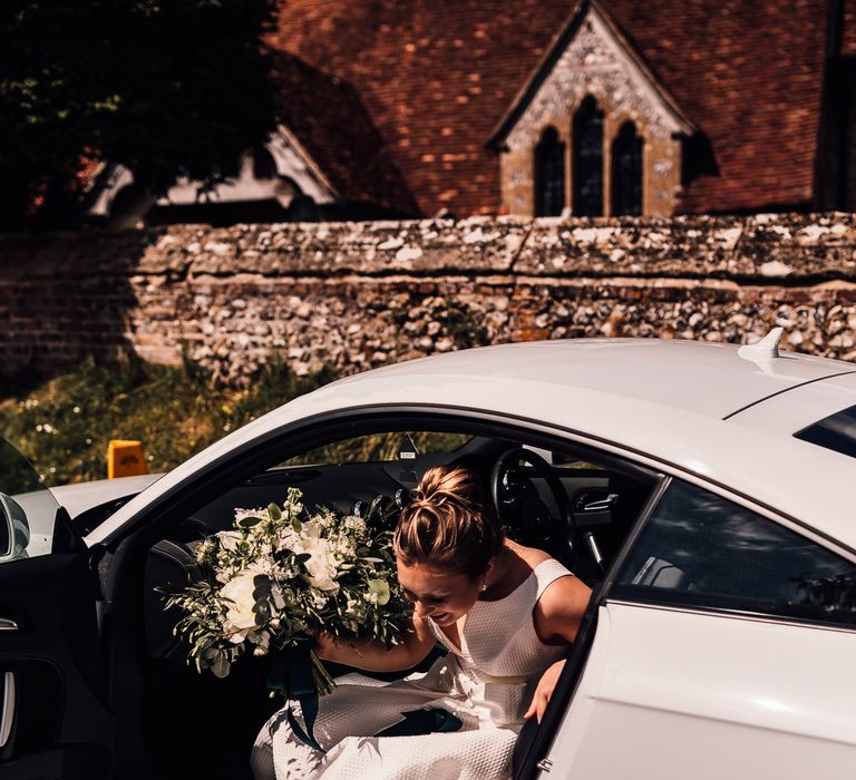 Bride arrives in white car on wedding day