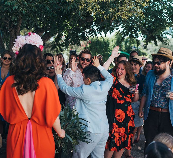 Brides celebrate with guests on their wedding day as they high five 