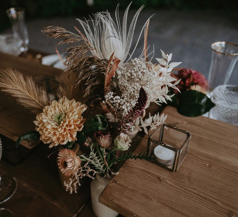 Orange, white red and grey dried flower centrepiece on wooden table for wedding breakfast and burnt orange wedding theme