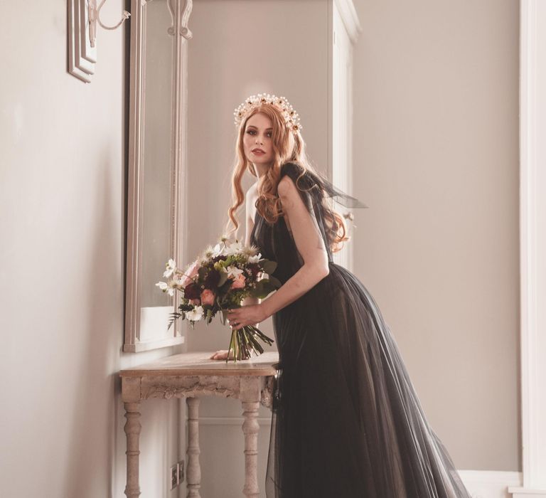 Bride with long wavy auburn hair wearing a headdress and black tulle wedding dress