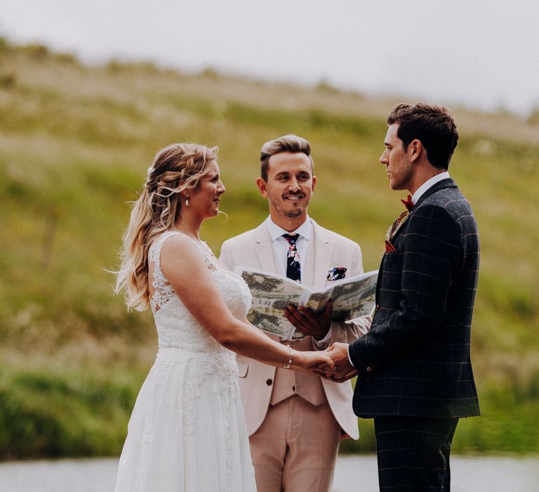 Bride & groom hold hands and look at one another on their wedding day as bride wears Justin Alexander gown