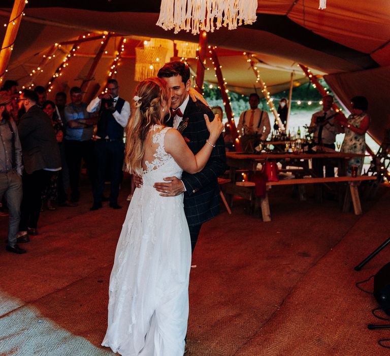 Bride & groom dance in tipi on their wedding day during their reception as wedding guests watch 