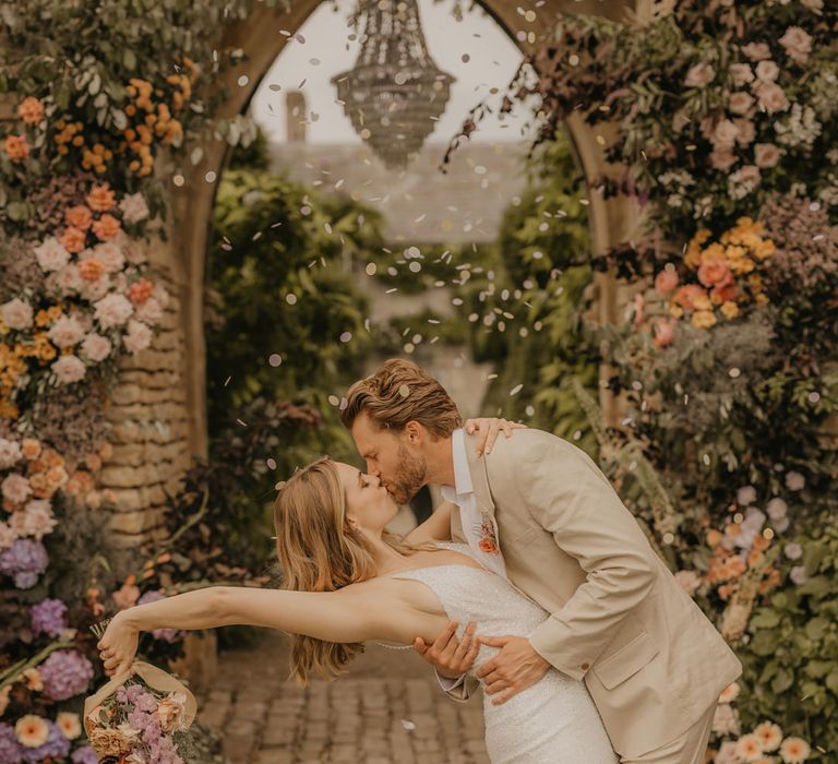 Groom in a beige suit leaning his bride over for a kiss in a sparkly Made With Love dress at Euridge Manor 