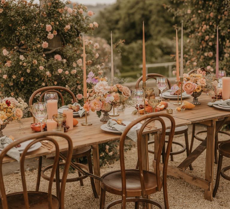 Outdoor wedding reception at Euridge Manor with orange taper candles, gold candlesticks, pastel orange and pink flowers and iridescent glassware