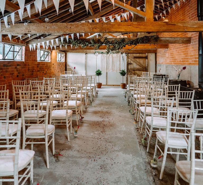 Wedding ceremony venue in barn complete with white chairs and rustic vibe