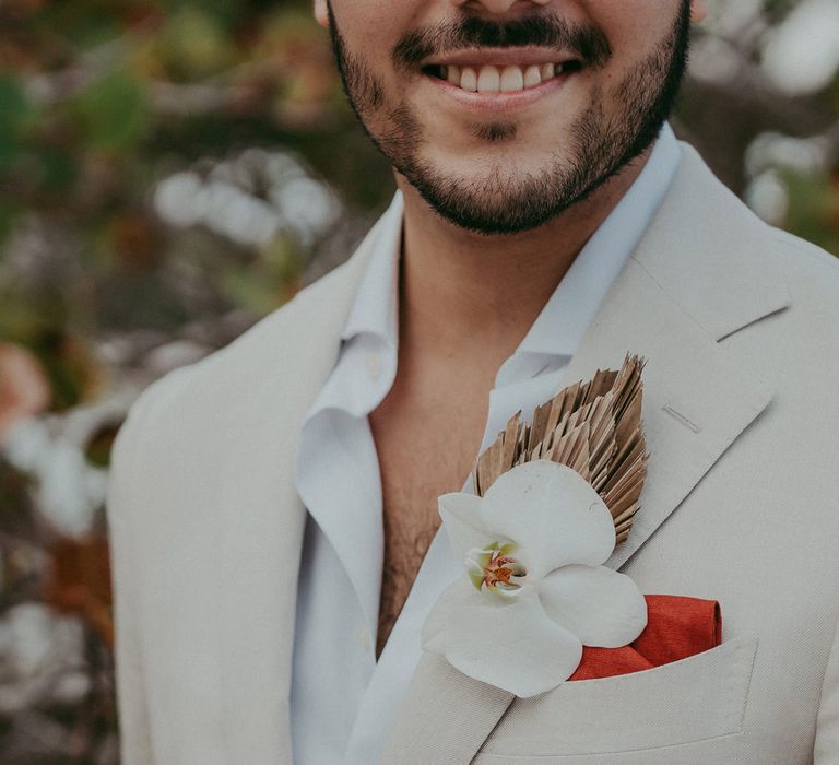 Destination wedding with groom in a linen suit wearing a white orchid buttonhole flower