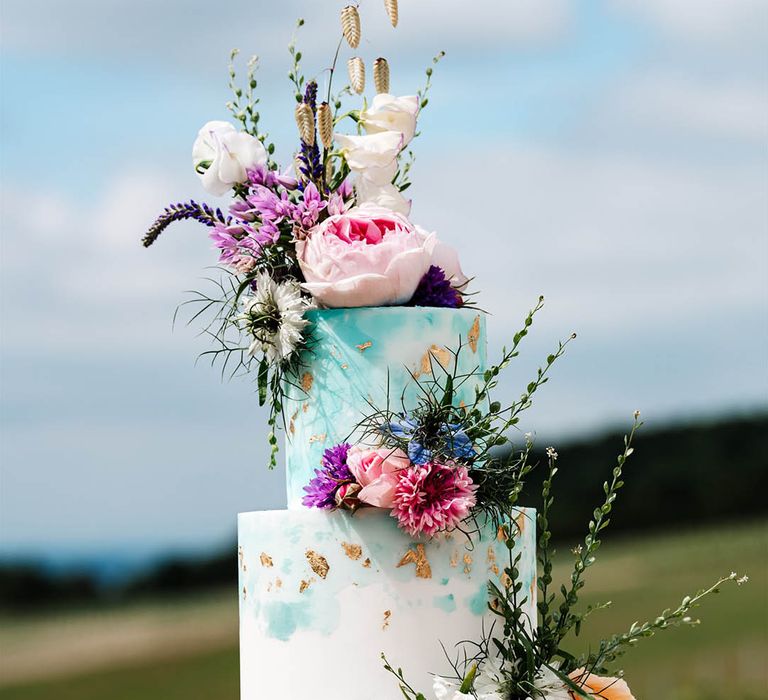 Turquoise and white buttercream wedding cake decorated with colourful wildflowers at Little Wold Vineyard