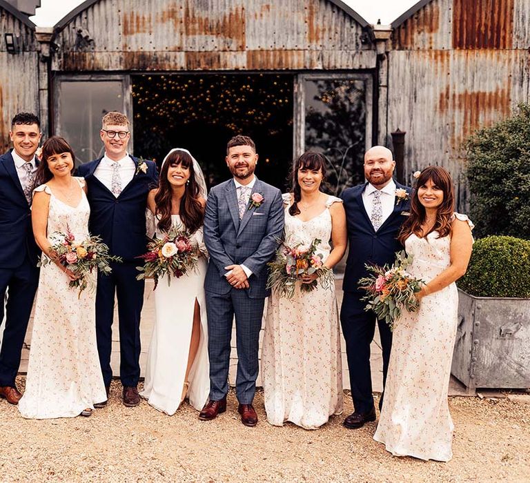 Bride & groom stand with their family outdoors after wedding ceremony