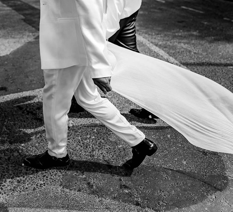 Groom in a white suit and billowing cape 