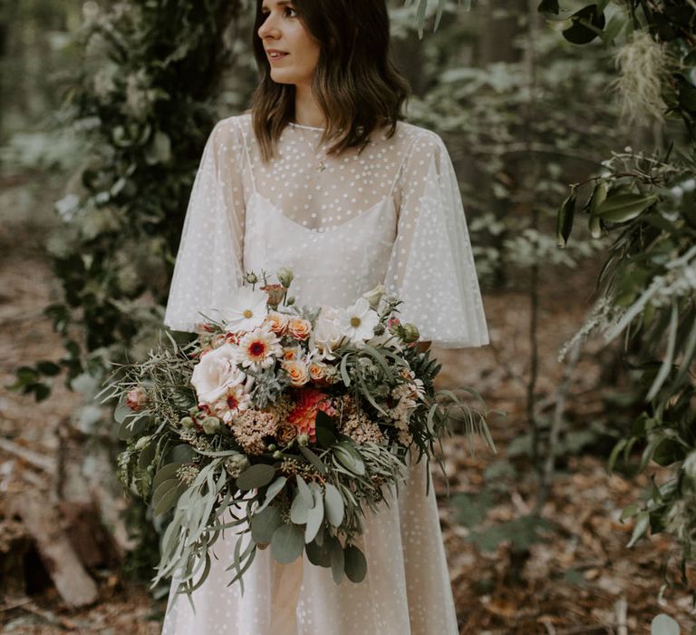 Bride holds her floral bouquet and looks away from camera