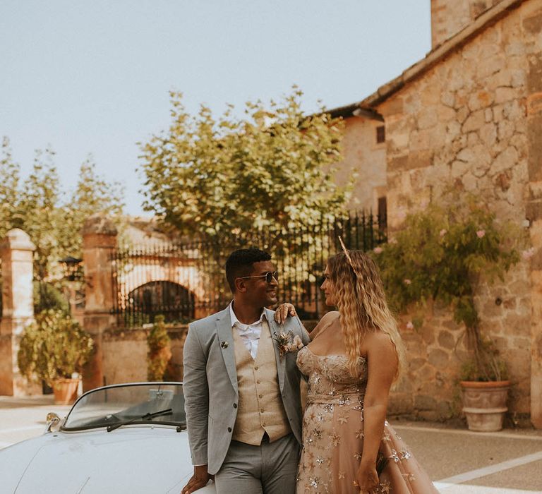 Bride & groom stand beside car on their wedding day