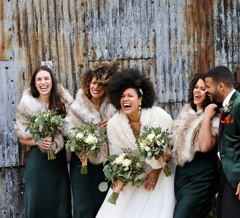 Bride laughs with her bridesmaids and groom on their wedding day