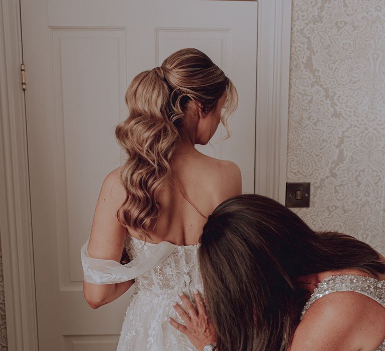 Bride has her dress done up on the morning of her wedding day