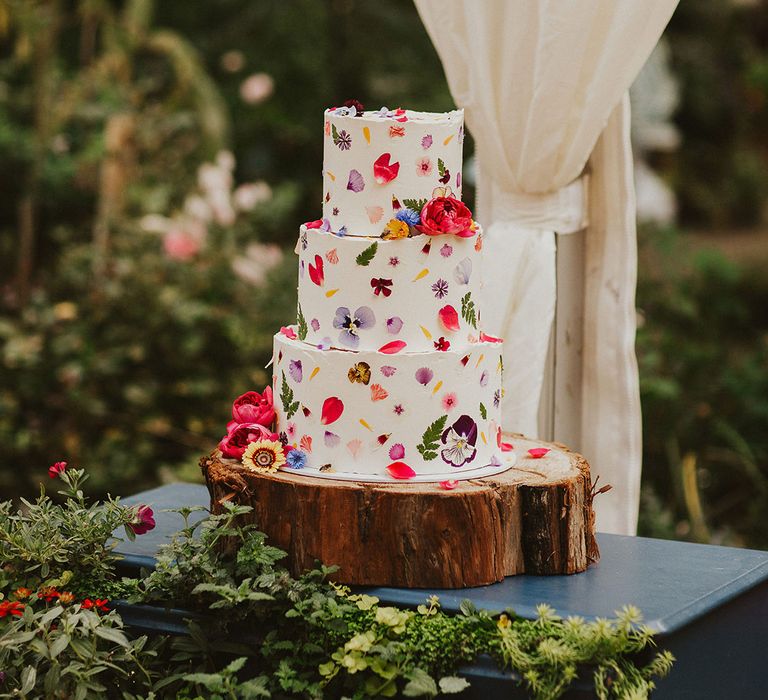 edible flower pressed wedding cake on a wooden tree slice cake stand for back garden clear marquee wedding 