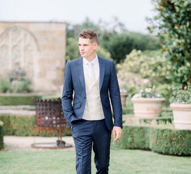 Groom wears wedding suit complete with white waistcoat and tie 